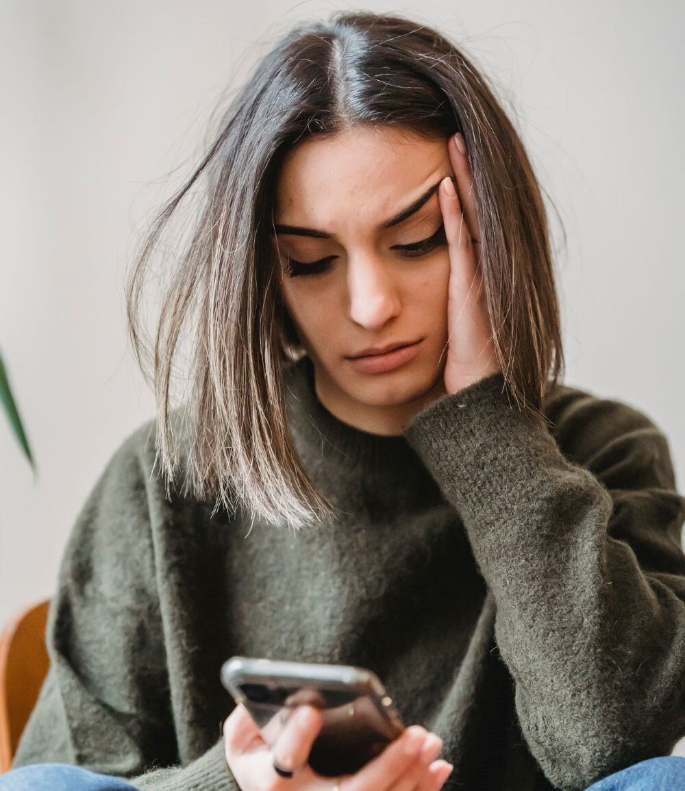 woman staring at her phone wondering about registering for educational programs