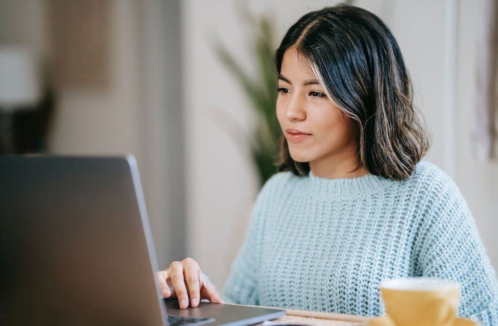 young woman smiling at her laptop after earning early-career microcredentials