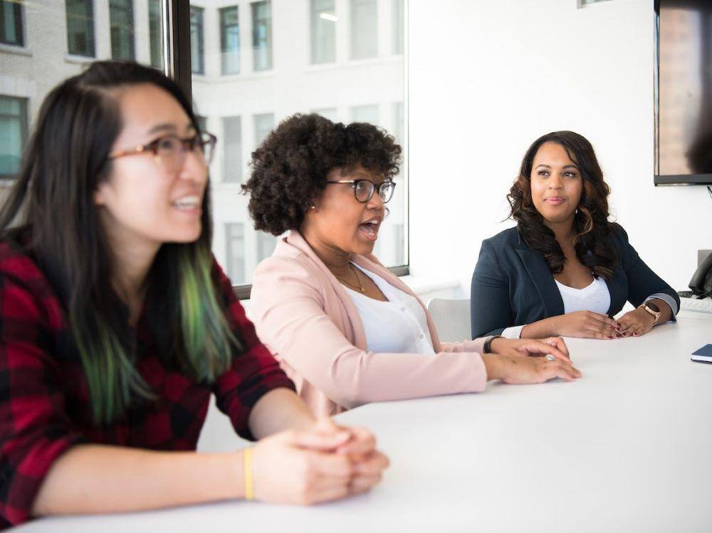 three women sitting at a table and participating in an open space event format