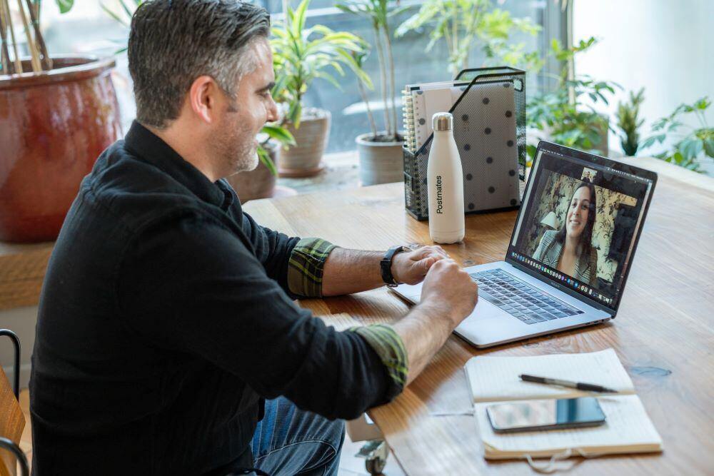 Online education volunteer at work - a success coach (man) talking with an adult learner (woman) via Zoom