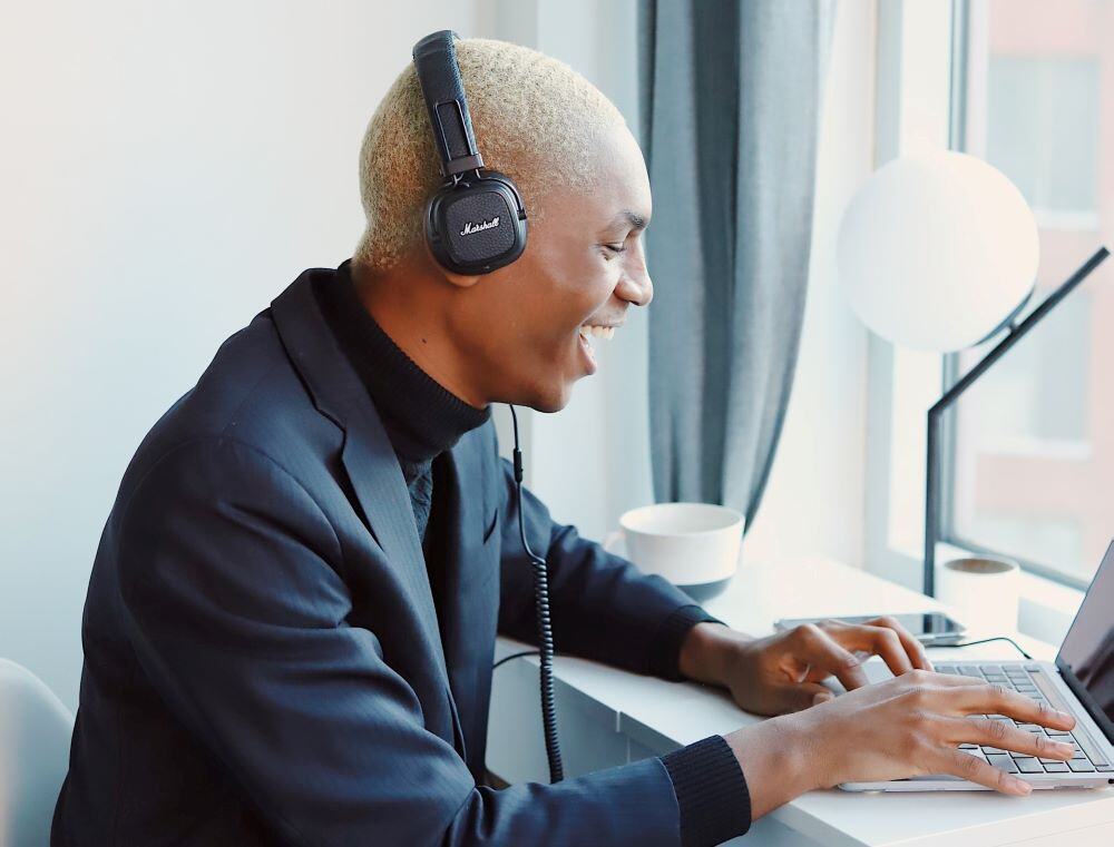 man in suit at laptop smiling and laughing at an event hosted by his association's year-round learning community