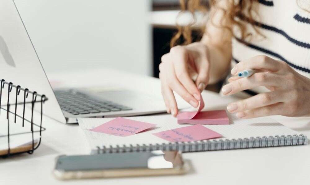 woman jotting down ideas on post-it notes for action mapping exercises