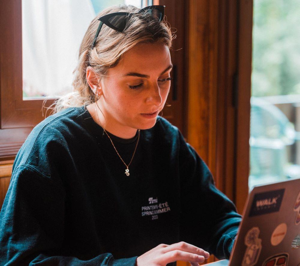 a woman reading something on her laptop getting a good idea from a for-profit professional development brand