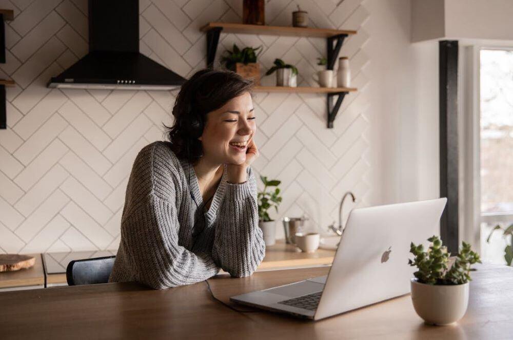 a woman sitting at her kitchen island enjoying association rituals on her laptop