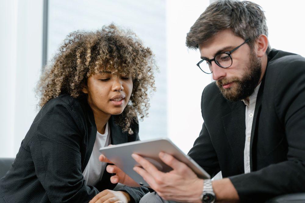 attract, support and retain adult learners like this man and woman in business suits looking at a tablet